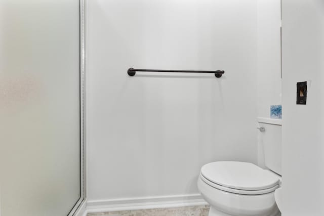 bathroom with baseboards, a shower with shower door, and toilet
