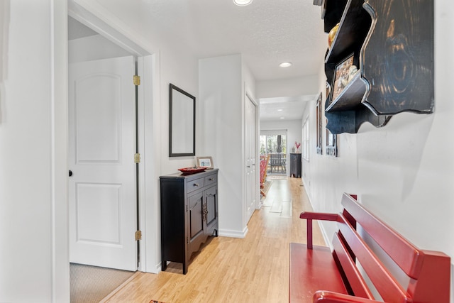 hall featuring baseboards, recessed lighting, and light wood finished floors