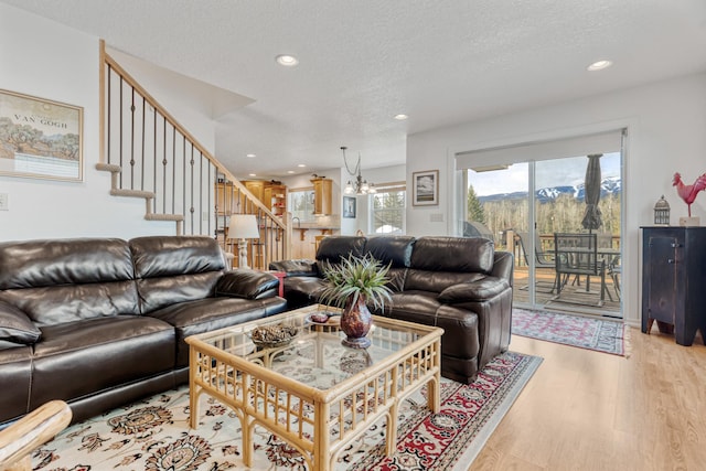 living area with a textured ceiling, stairway, a chandelier, light wood-style floors, and recessed lighting