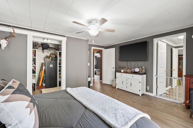 bedroom featuring wood finished floors, a closet, a ceiling fan, and baseboards