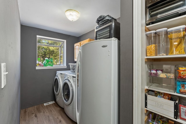clothes washing area featuring wood finished floors, separate washer and dryer, laundry area, baseboards, and visible vents