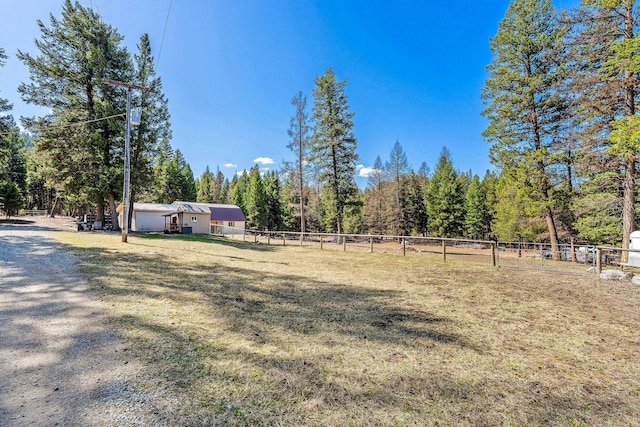 view of yard with fence and a rural view
