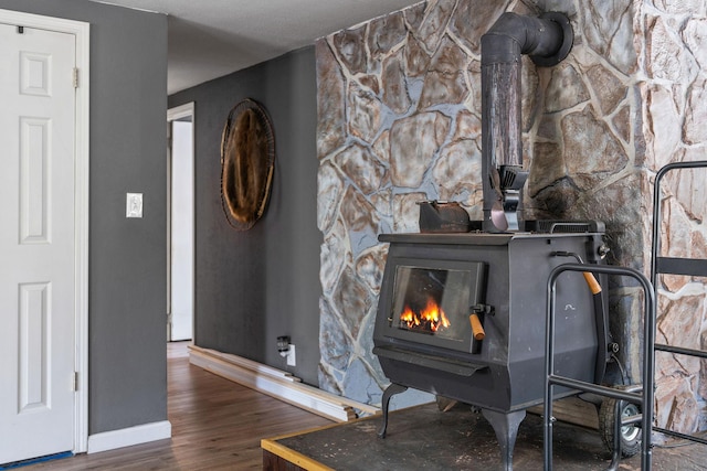 room details with a wood stove, wood finished floors, and baseboards