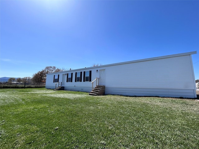 rear view of property featuring a yard and entry steps