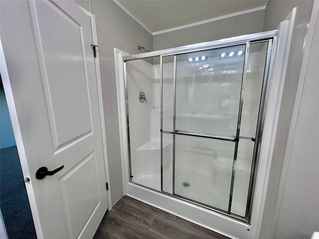 bathroom with crown molding, a shower stall, and wood finished floors