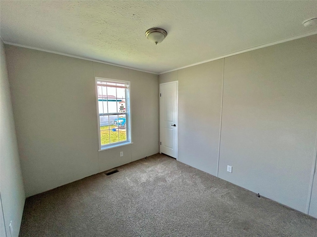 unfurnished room featuring carpet flooring, a textured ceiling, visible vents, and ornamental molding