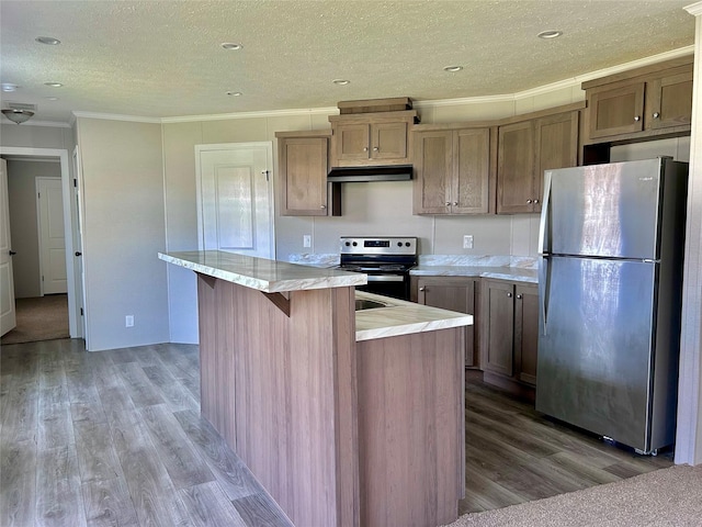 kitchen with a textured ceiling, appliances with stainless steel finishes, under cabinet range hood, and light wood-style floors