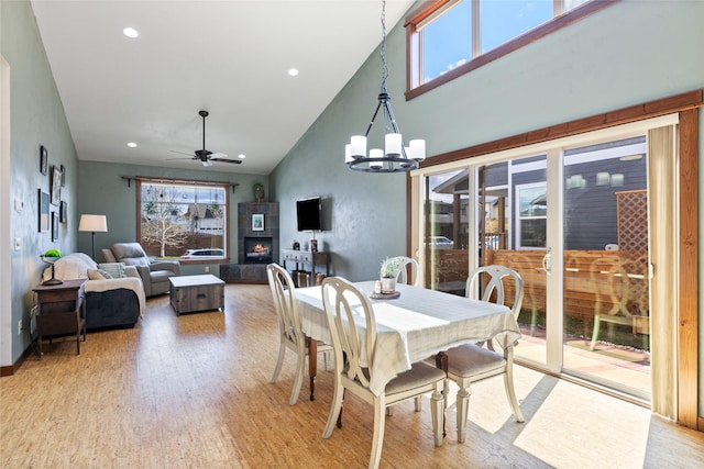 3383 Sora Way, Bozeman, MT 59718 - dining area with light wood-style flooring, a ceiling fan, a tile fireplace, high vaulted ceiling, and a chandelier