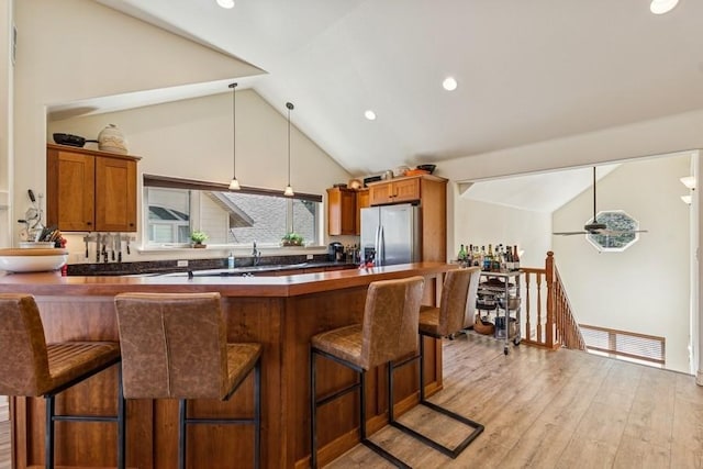 kitchen with a kitchen bar, stainless steel refrigerator with ice dispenser, and lofted ceiling