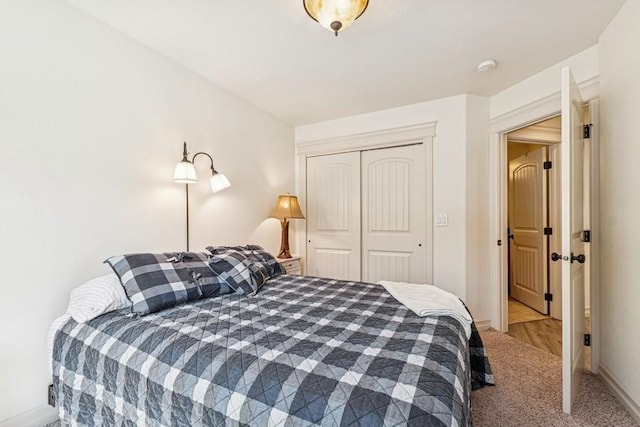 carpeted bedroom featuring baseboards and a closet