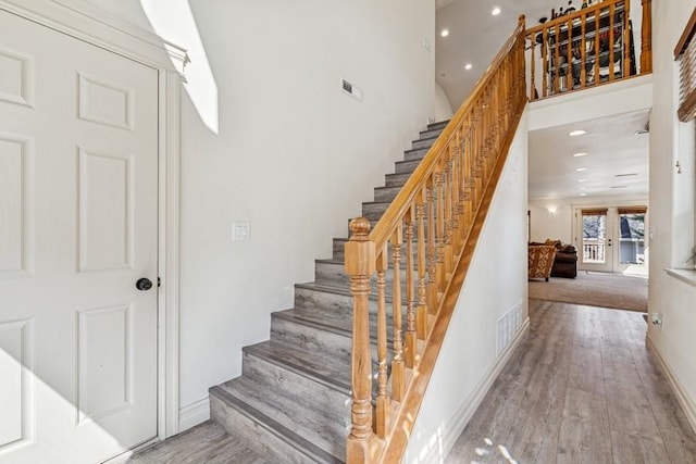 staircase featuring baseboards, visible vents, wood finished floors, and recessed lighting