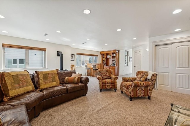 living room with visible vents, recessed lighting, a wood stove, and carpet floors