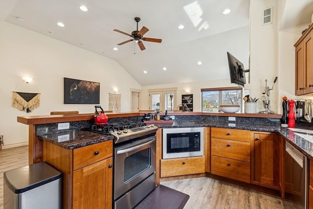 kitchen featuring visible vents, light wood-style floors, appliances with stainless steel finishes, and lofted ceiling