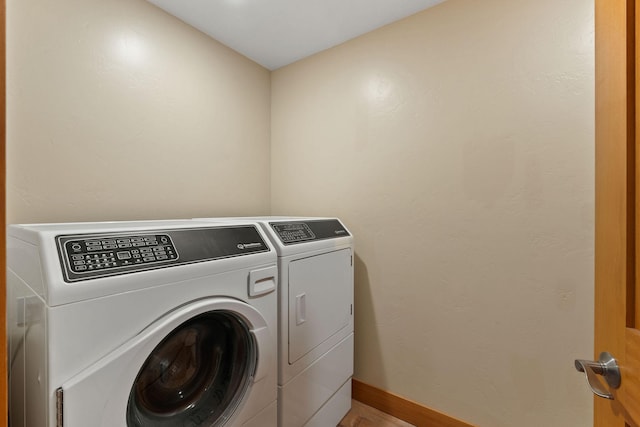 washroom featuring light wood-style flooring, independent washer and dryer, laundry area, and baseboards