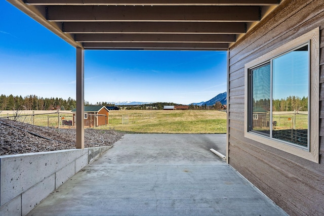 view of patio with an outdoor structure, a mountain view, and fence