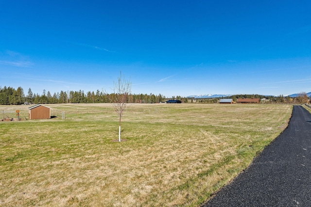 view of yard with a storage unit, a rural view, and an outdoor structure