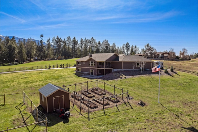 back of house featuring a fenced backyard, a yard, a garden, an outbuilding, and a shed