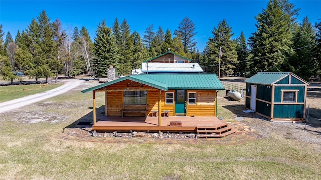 view of front of home with a deck, an outdoor structure, a front lawn, and metal roof