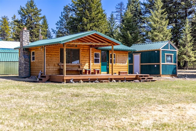 view of front of house with a chimney, a front lawn, metal roof, and log veneer siding