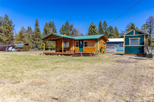 view of front of property with a deck, an outbuilding, a front yard, and metal roof