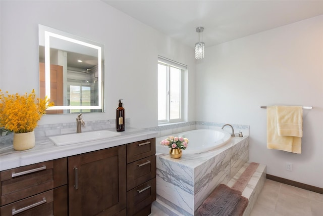bathroom with a garden tub, vanity, tile patterned flooring, and baseboards