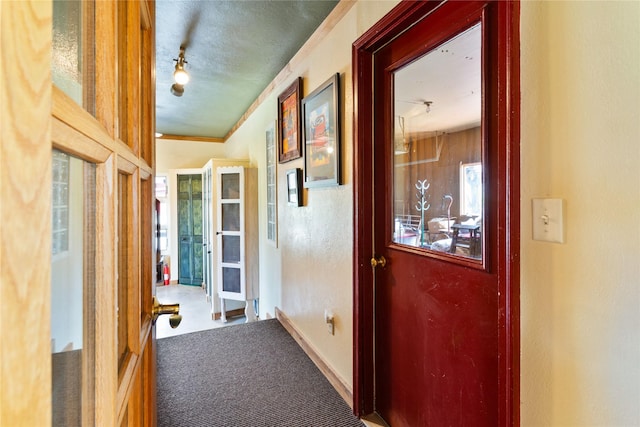 corridor featuring a textured ceiling, a textured wall, and carpet floors