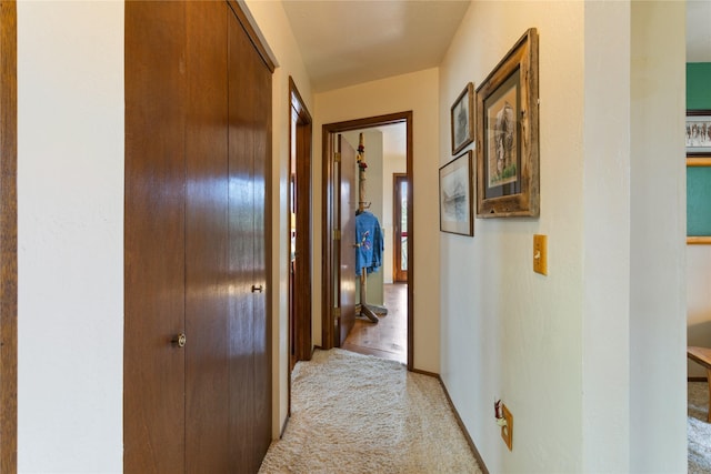 hallway featuring baseboards and light carpet