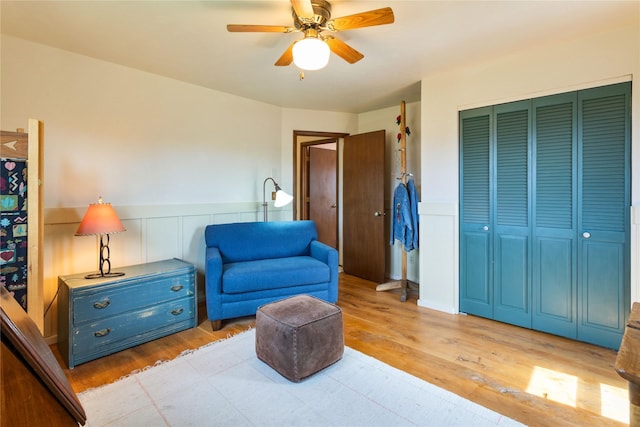 living area with wood finished floors, a ceiling fan, and wainscoting