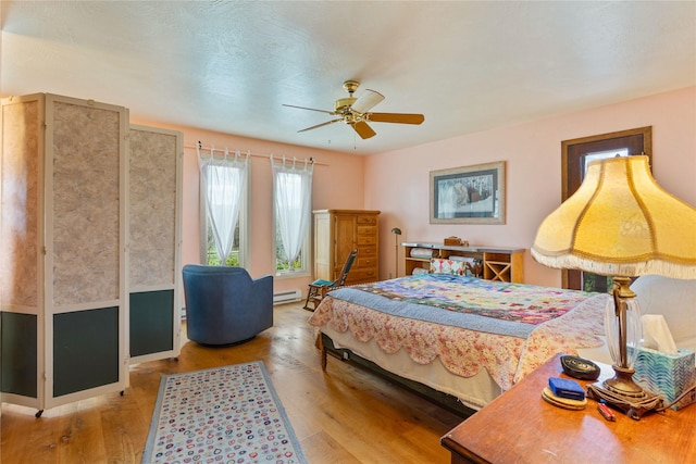 bedroom with wood finished floors, a ceiling fan, and a baseboard radiator