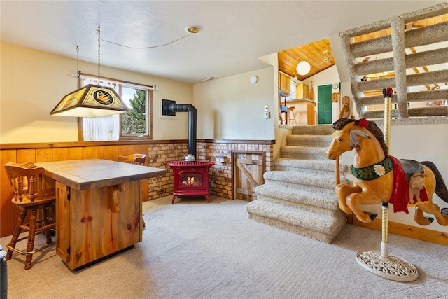 interior space featuring a wood stove, wainscoting, wood walls, and light carpet