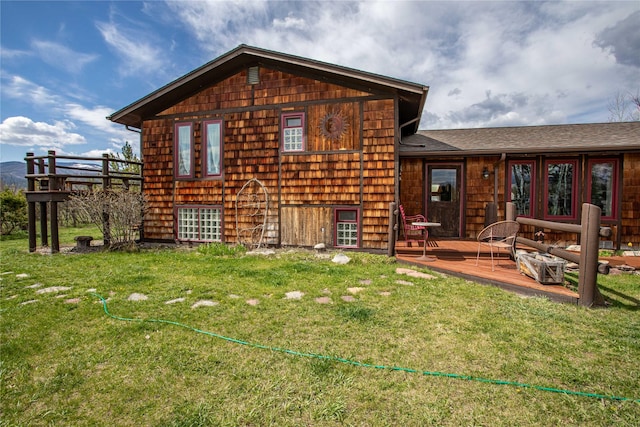 back of house featuring roof with shingles, a deck, and a yard