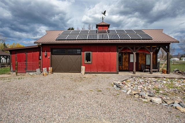 exterior space with gravel driveway, roof mounted solar panels, metal roof, and an attached garage