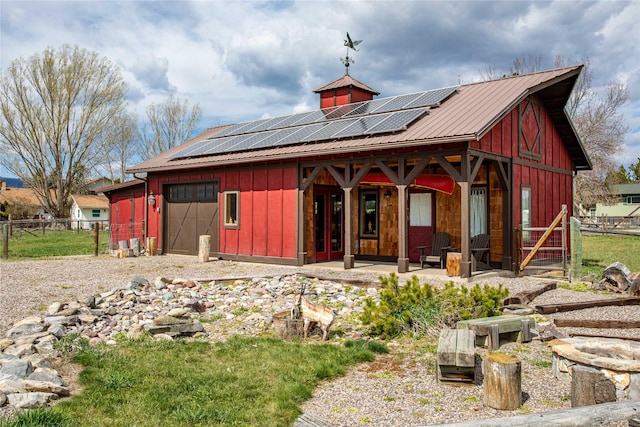 rear view of property with covered porch, fence, board and batten siding, and roof mounted solar panels