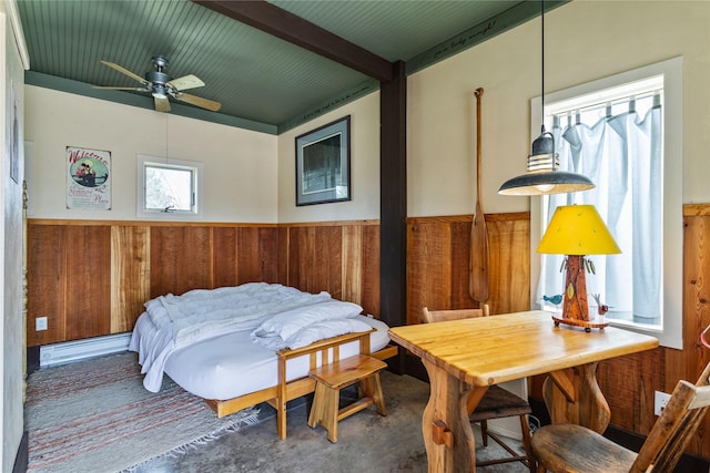 bedroom featuring wainscoting, beamed ceiling, concrete flooring, and wooden walls