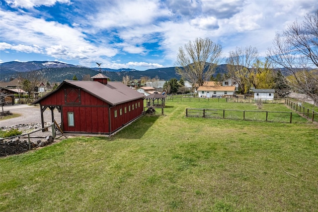 exterior space featuring an outdoor structure, a mountain view, and fence