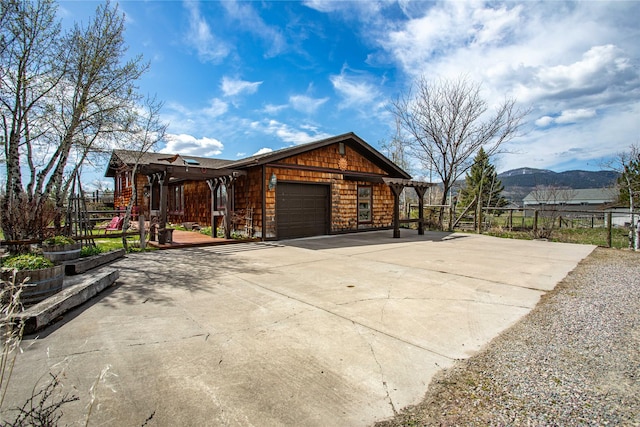 view of side of property with concrete driveway, a mountain view, an attached garage, and fence