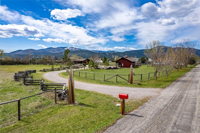 view of community featuring a rural view, a yard, and a mountain view