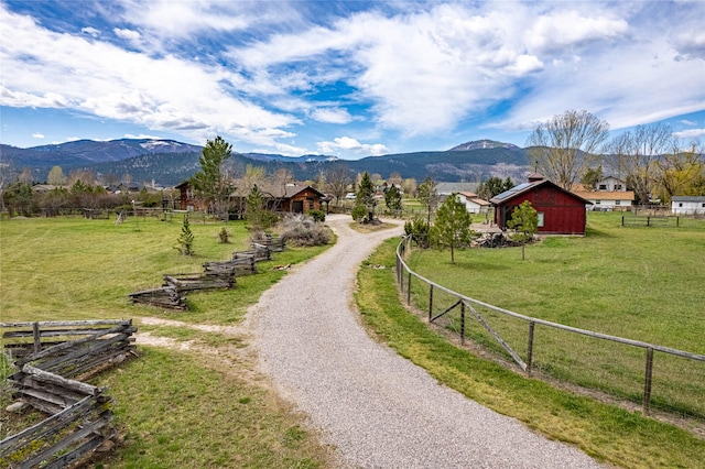 view of community featuring a lawn, a mountain view, a rural view, and fence