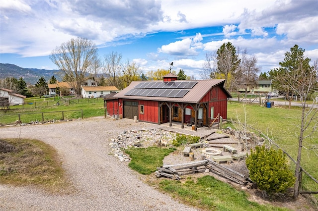 view of outbuilding featuring an outdoor structure, gravel driveway, solar panels, and fence