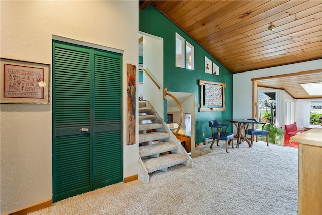 staircase featuring baseboards, wooden ceiling, carpet flooring, and vaulted ceiling