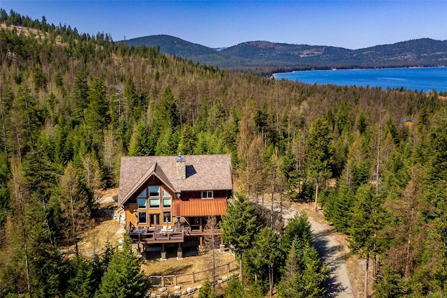 drone / aerial view with a water and mountain view and a wooded view
