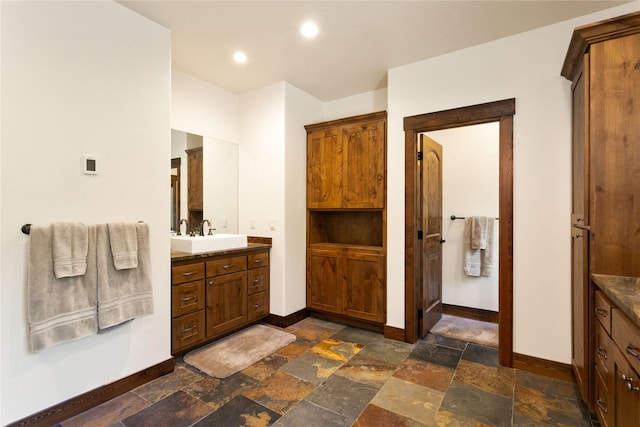 bathroom with vanity, stone tile flooring, and baseboards