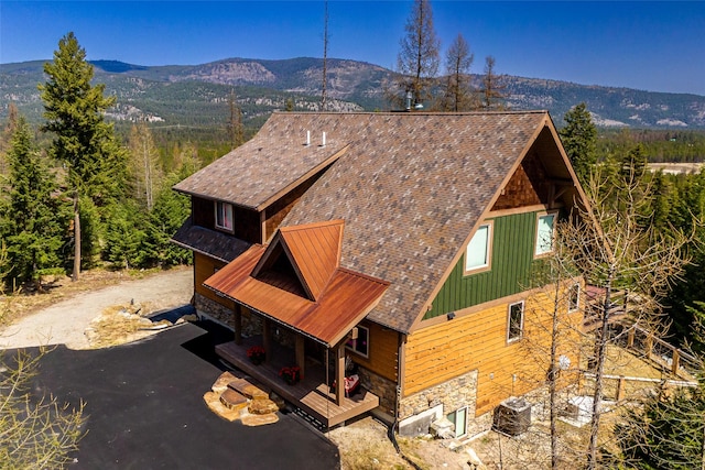 exterior space with a mountain view, stone siding, and dirt driveway