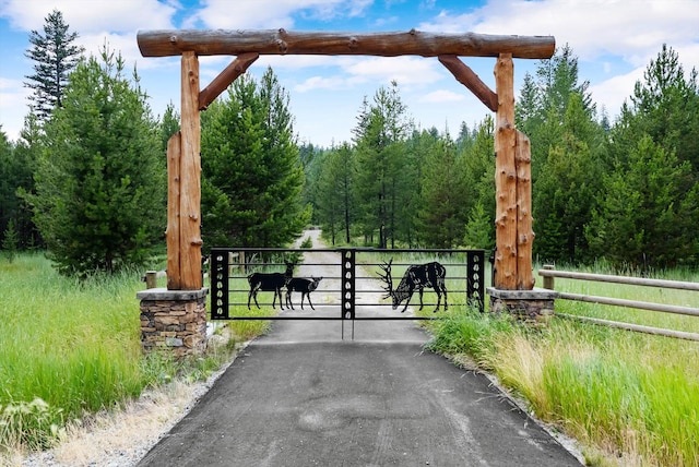view of gate with fence and a forest view