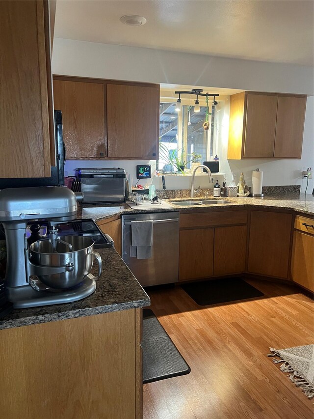 69571 Big Sam Ln, Arlee, MT 59821 - kitchen featuring stainless steel dishwasher, a sink, light wood finished floors, and dark stone counters