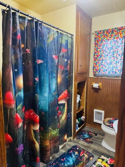bathroom with toilet, wooden walls, and a shower with curtain