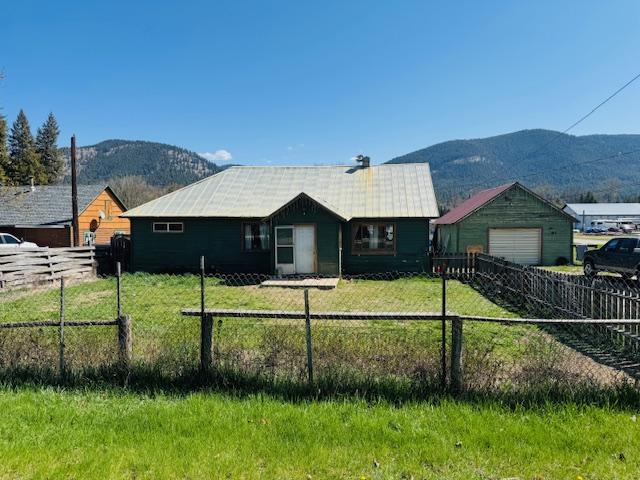 view of front of home featuring a mountain view, fence private yard, and a front lawn