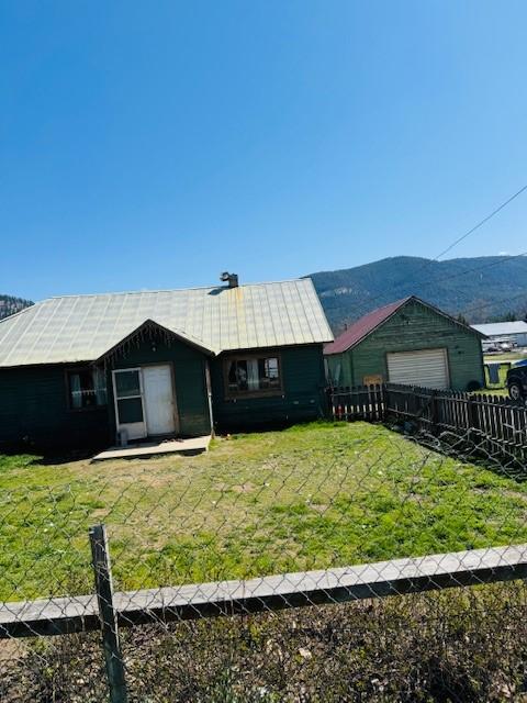 view of front of house with metal roof, a front lawn, an attached garage, and fence