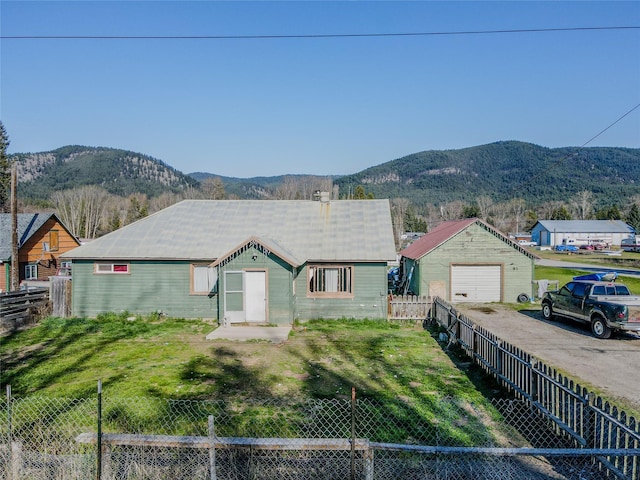 view of front facade featuring a fenced backyard, aphalt driveway, a mountain view, and a garage