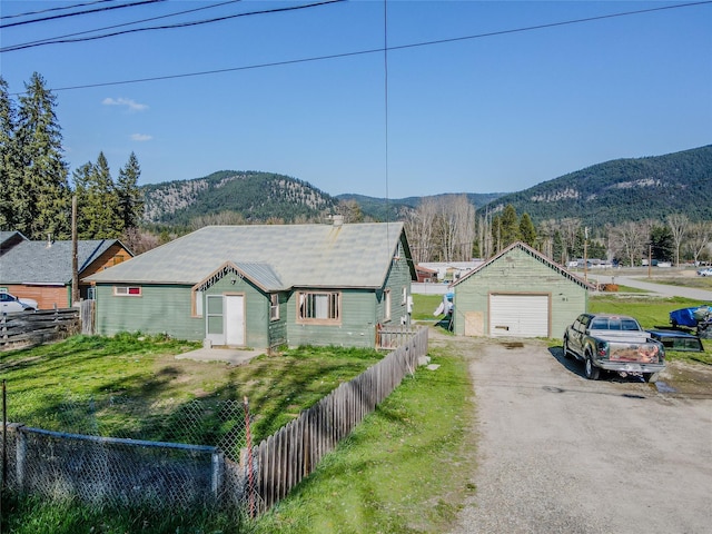 ranch-style house featuring a garage, a mountain view, fence, and driveway